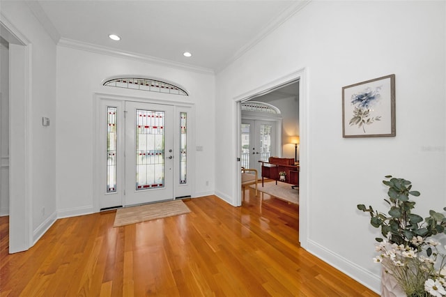 foyer entrance with french doors, baseboards, crown molding, and light wood finished floors