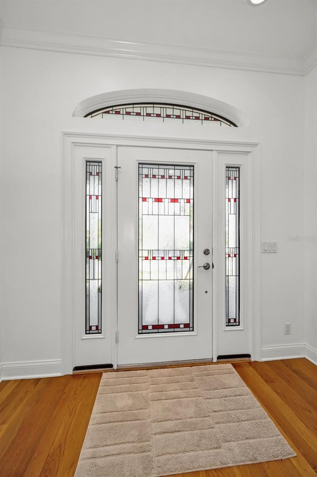 entrance foyer featuring ornamental molding, baseboards, and wood finished floors