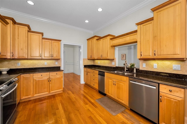 kitchen with stainless steel appliances, a sink, dark stone counters, light wood finished floors, and crown molding