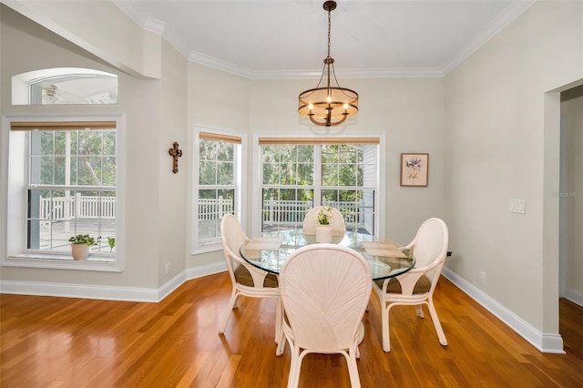 dining space with baseboards, a chandelier, wood finished floors, and ornamental molding