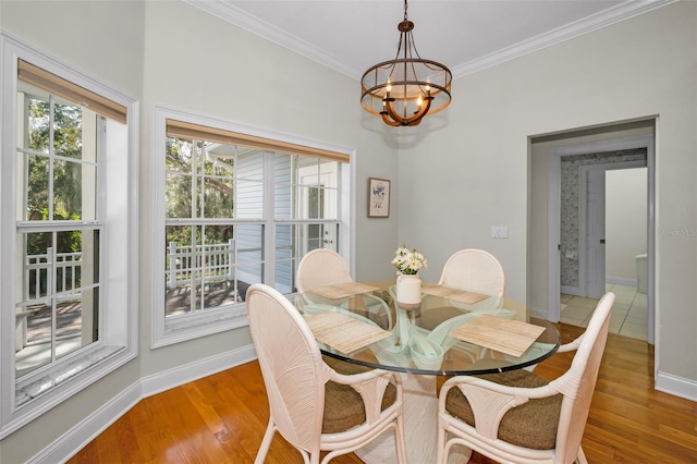 dining room featuring an inviting chandelier, crown molding, baseboards, and wood finished floors