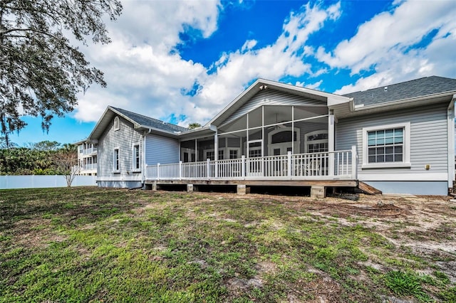 rear view of property featuring a lawn, a wooden deck, a sunroom, and fence