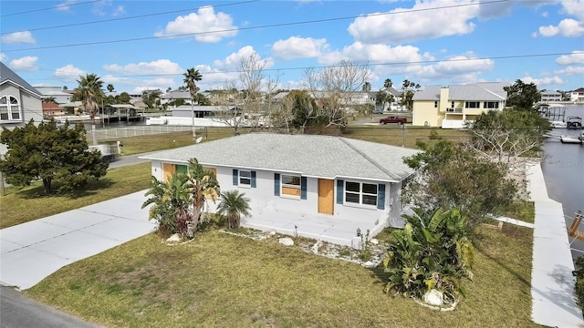 view of front of property featuring a shingled roof, a residential view, and a front yard