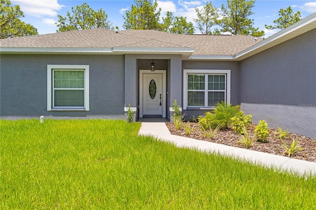 11345 Thrasher Ave, Weeki Wachee, FL 34614 - doorway to property with stucco siding, a shingled roof, and a yard