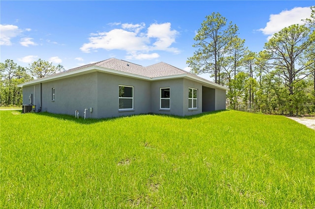11345 Thrasher Ave, Weeki Wachee, FL 34614 - view of side of property featuring stucco siding, central AC unit, a yard, and a shingled roof