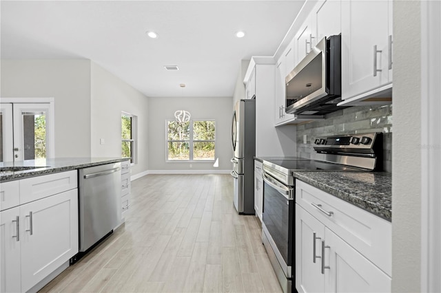 11345 Thrasher Ave, Weeki Wachee, FL 34614 - kitchen featuring appliances with stainless steel finishes, white cabinets, dark stone countertops, light wood-style flooring, and recessed lighting