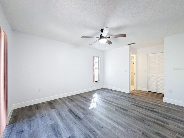 spare room with ceiling fan, dark wood-type flooring, and a textured ceiling