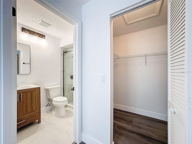 bathroom featuring a textured ceiling, toilet, vanity, and a shower