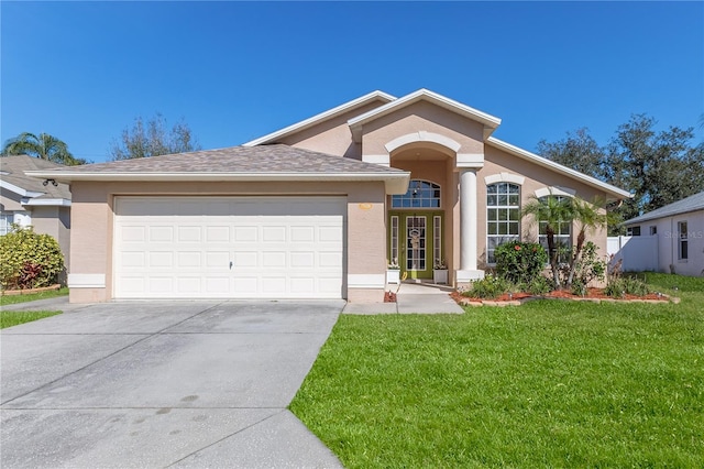 view of front of home featuring a garage, a front yard, concrete driveway, and stucco siding