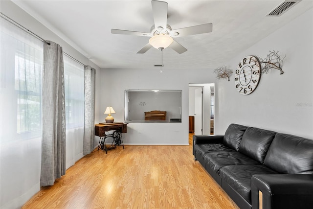 living area featuring a ceiling fan, light wood-type flooring, visible vents, and baseboards