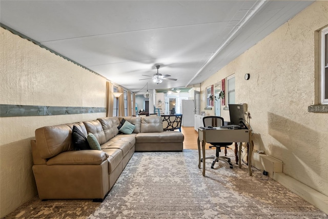 living room featuring ceiling fan, wood finished floors, and a textured wall