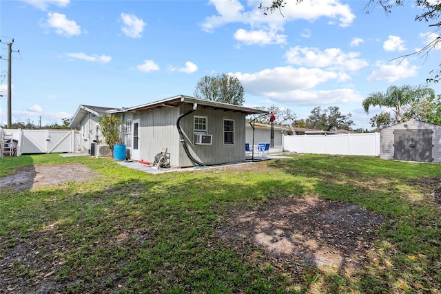 rear view of property featuring a storage unit, cooling unit, a fenced backyard, and a gate