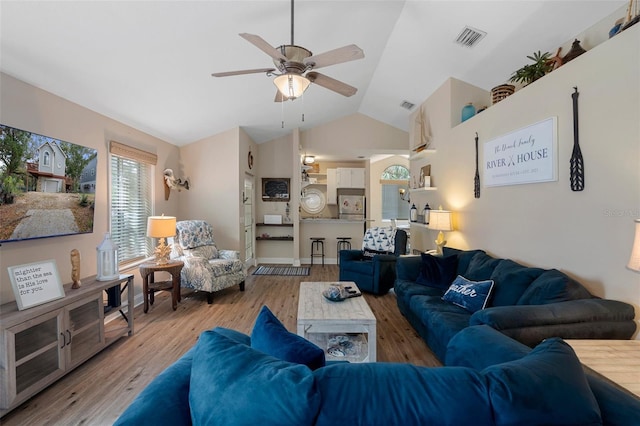 living area with lofted ceiling, a ceiling fan, baseboards, visible vents, and light wood-style floors