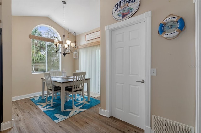 dining space featuring a notable chandelier, lofted ceiling, visible vents, light wood-style flooring, and baseboards