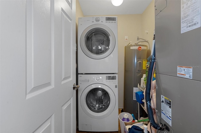 laundry room featuring stacked washer and clothes dryer, electric water heater, heating unit, and laundry area