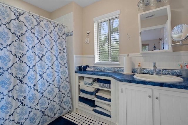 full bathroom featuring visible vents, a wainscoted wall, tile patterned floors, curtained shower, and vanity