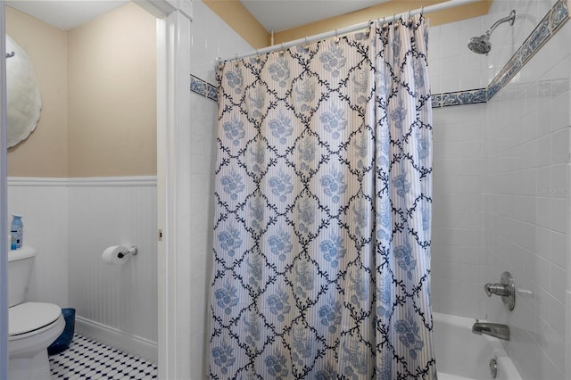 bathroom with shower / tub combo, a wainscoted wall, and toilet