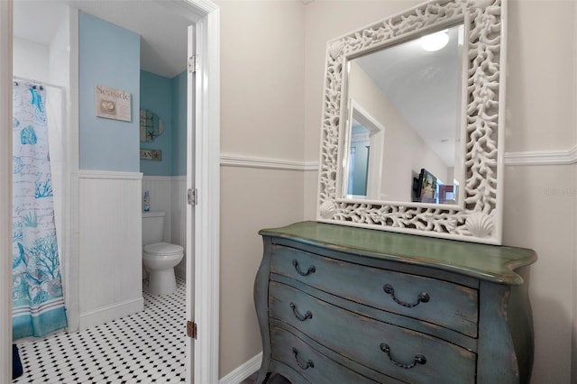 full bath featuring toilet, vanity, and wainscoting