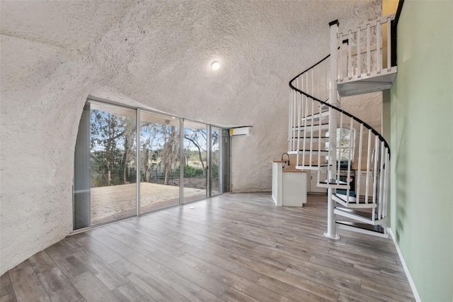 entryway featuring a textured ceiling, floor to ceiling windows, a high ceiling, and light hardwood / wood-style floors