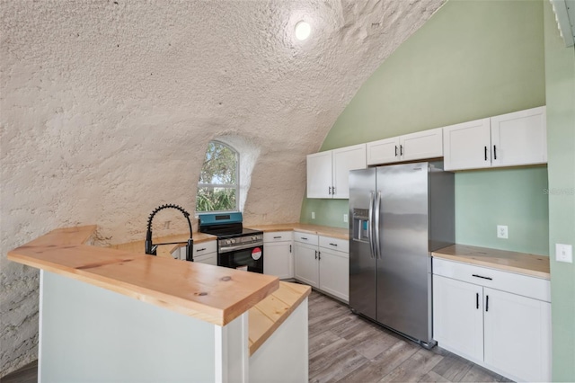 kitchen with stainless steel appliances, white cabinets, lofted ceiling, light hardwood / wood-style floors, and kitchen peninsula