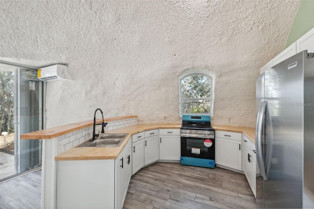 kitchen featuring sink, butcher block counters, stainless steel appliances, white cabinets, and a wall mounted AC