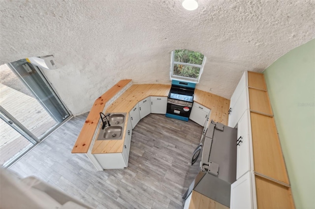 kitchen with white cabinets, oven, a textured ceiling, and light hardwood / wood-style flooring