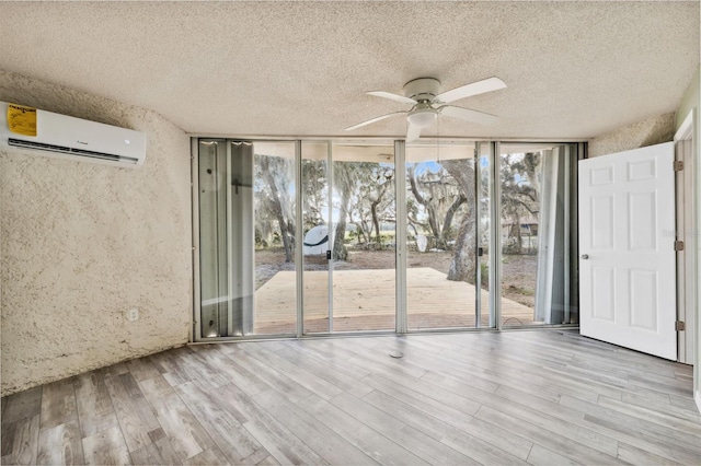 interior space featuring floor to ceiling windows, light wood-type flooring, a textured ceiling, ceiling fan, and a wall mounted AC