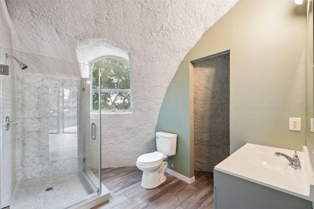 bathroom featuring hardwood / wood-style flooring, vanity, a shower with door, and toilet