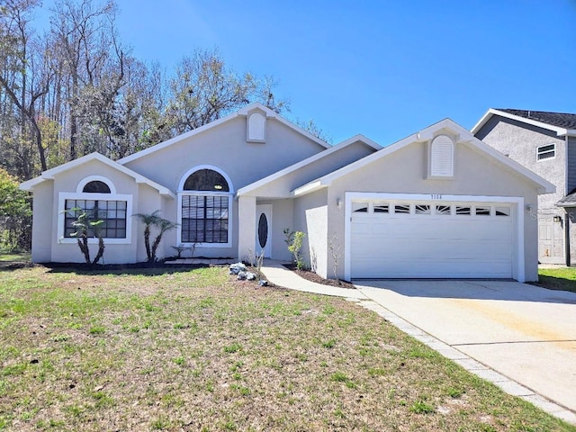 ranch-style house featuring an attached garage, a front lawn, concrete driveway, and stucco siding