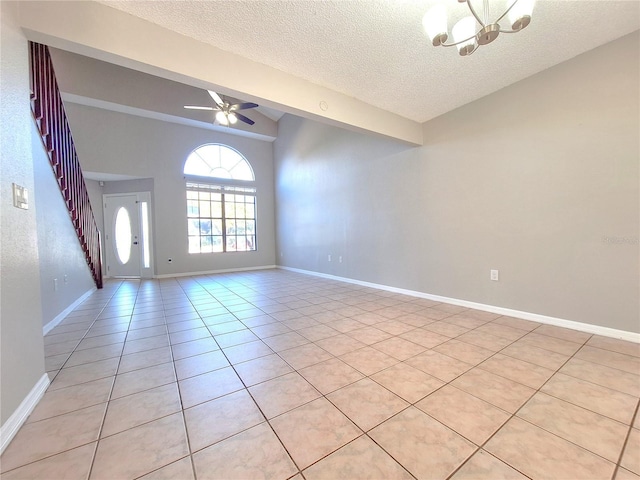 unfurnished room featuring lofted ceiling, a textured ceiling, light tile patterned flooring, ceiling fan with notable chandelier, and baseboards