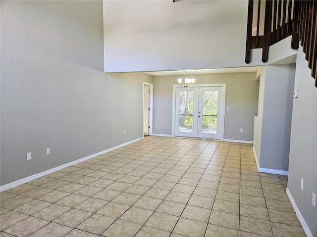 empty room with light tile patterned floors, baseboards, a notable chandelier, and french doors