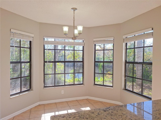 unfurnished dining area featuring a wealth of natural light, baseboards, a textured ceiling, and light tile patterned flooring