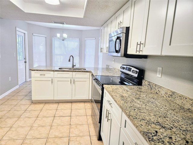 kitchen with a raised ceiling, appliances with stainless steel finishes, a peninsula, a textured ceiling, and a sink