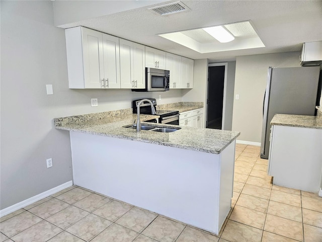 kitchen featuring light stone counters, a peninsula, visible vents, white cabinetry, and appliances with stainless steel finishes