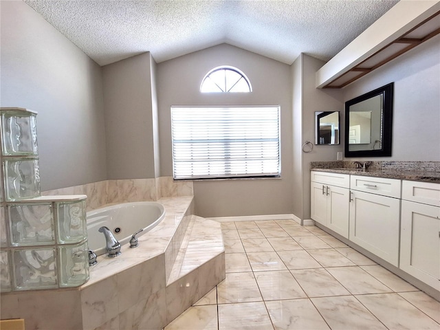 bathroom with baseboards, lofted ceiling, a whirlpool tub, a textured ceiling, and vanity