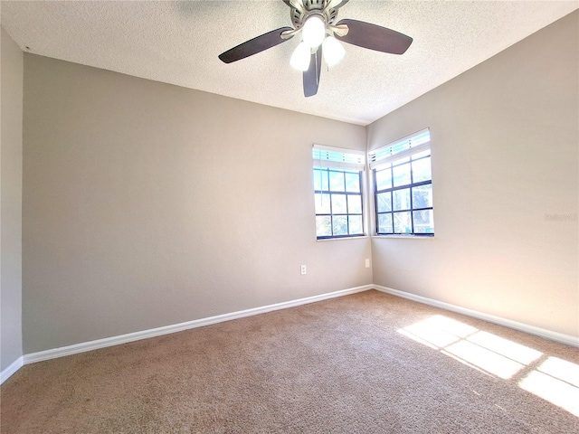 empty room featuring a ceiling fan, carpet, a textured ceiling, and baseboards