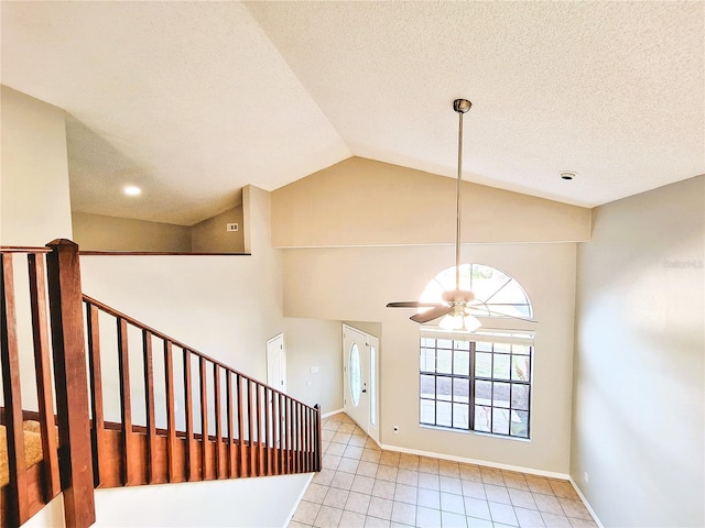 entrance foyer with lofted ceiling, a ceiling fan, a textured ceiling, baseboards, and stairs