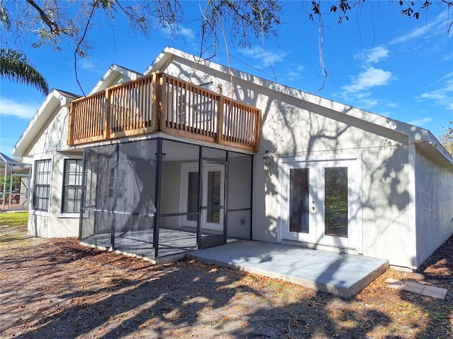 rear view of house featuring french doors, a patio area, a balcony, and stucco siding