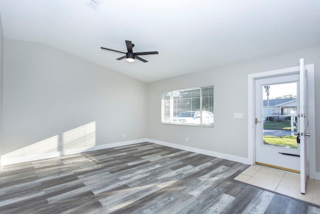 empty room with lofted ceiling, a textured ceiling, baseboards, and wood finished floors