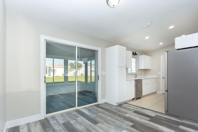 kitchen with light wood finished floors, white cabinetry, appliances with stainless steel finishes, and light countertops