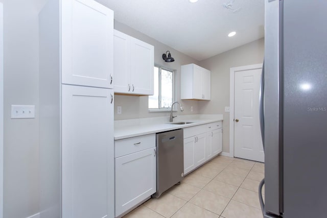 kitchen featuring stainless steel appliances, white cabinets, light countertops, and a sink