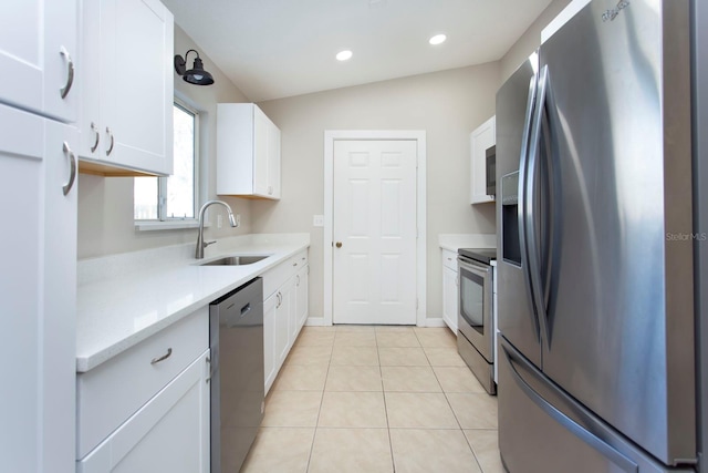 kitchen featuring stainless steel appliances, white cabinetry, a sink, and light tile patterned floors