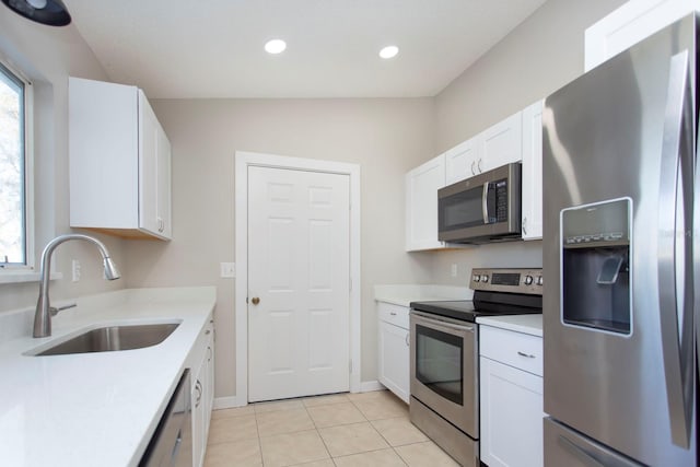 kitchen with stainless steel appliances, a sink, white cabinetry, a healthy amount of sunlight, and light countertops