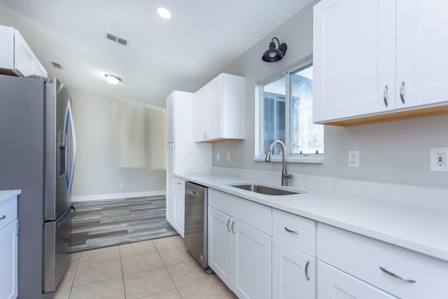 kitchen with stainless steel appliances, light countertops, light tile patterned flooring, and a sink