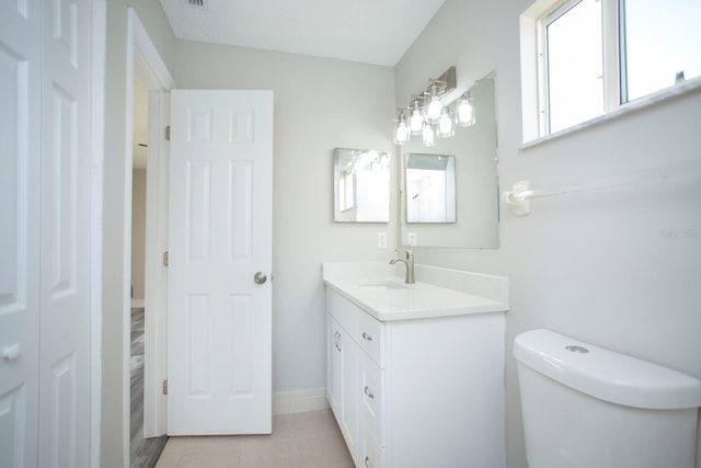 bathroom with toilet, tile patterned floors, baseboards, and vanity