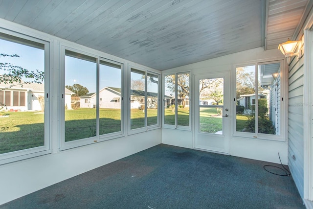 unfurnished sunroom featuring lofted ceiling, wooden ceiling, a residential view, and a wealth of natural light