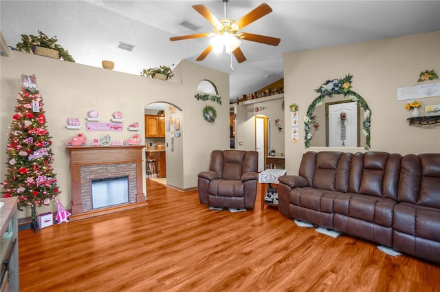 living room featuring light wood-type flooring, vaulted ceiling, a fireplace, and ceiling fan