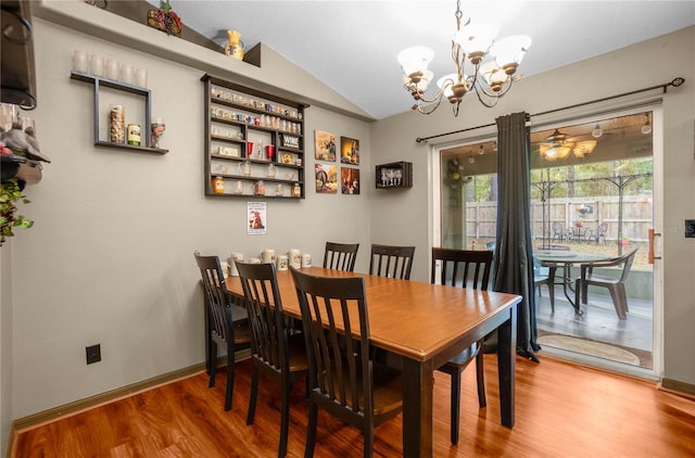 dining space featuring hardwood / wood-style flooring, vaulted ceiling, and a notable chandelier