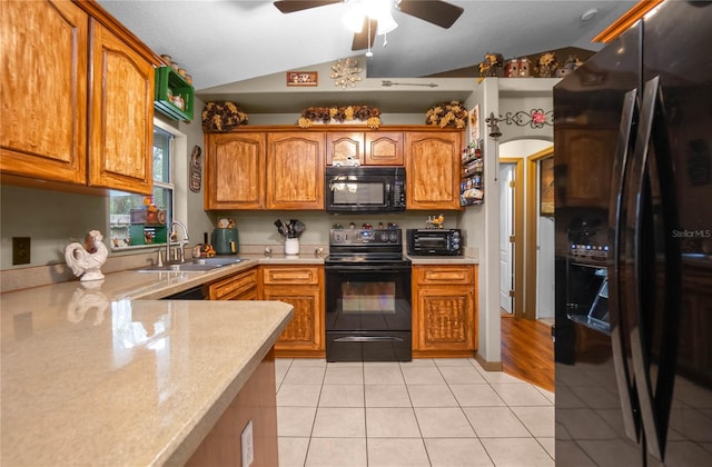 kitchen featuring black appliances, ceiling fan, vaulted ceiling, light tile patterned floors, and sink