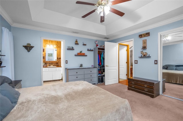 carpeted bedroom featuring sink, ornamental molding, ceiling fan, and a raised ceiling